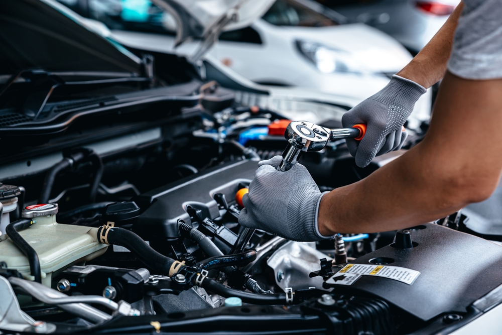Mechanic repairing a car engine using tools and AI diagnostics.
